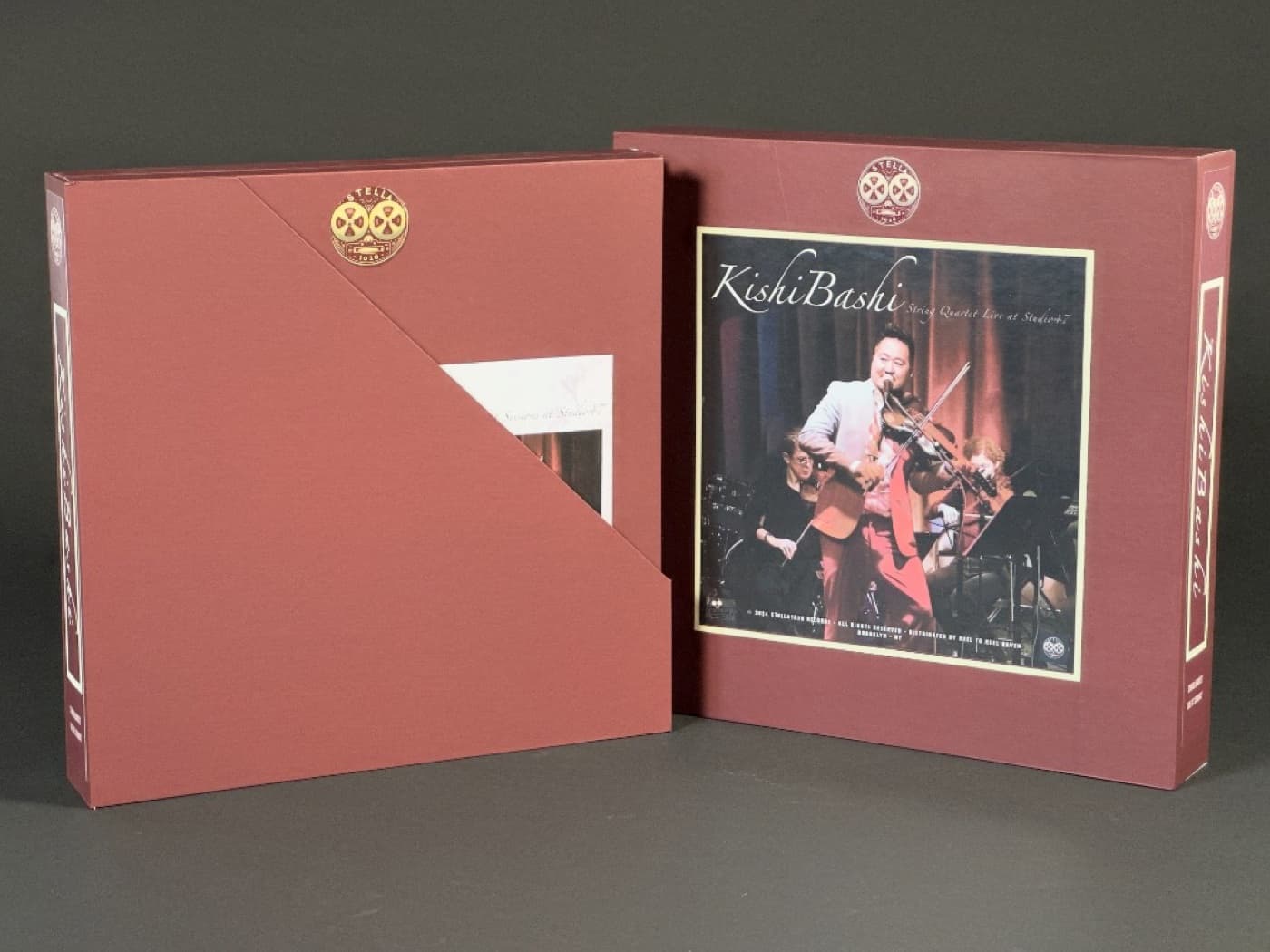 Two burgundy Kishi Bashi album boxes side by side with gold Stella Tapes emblem